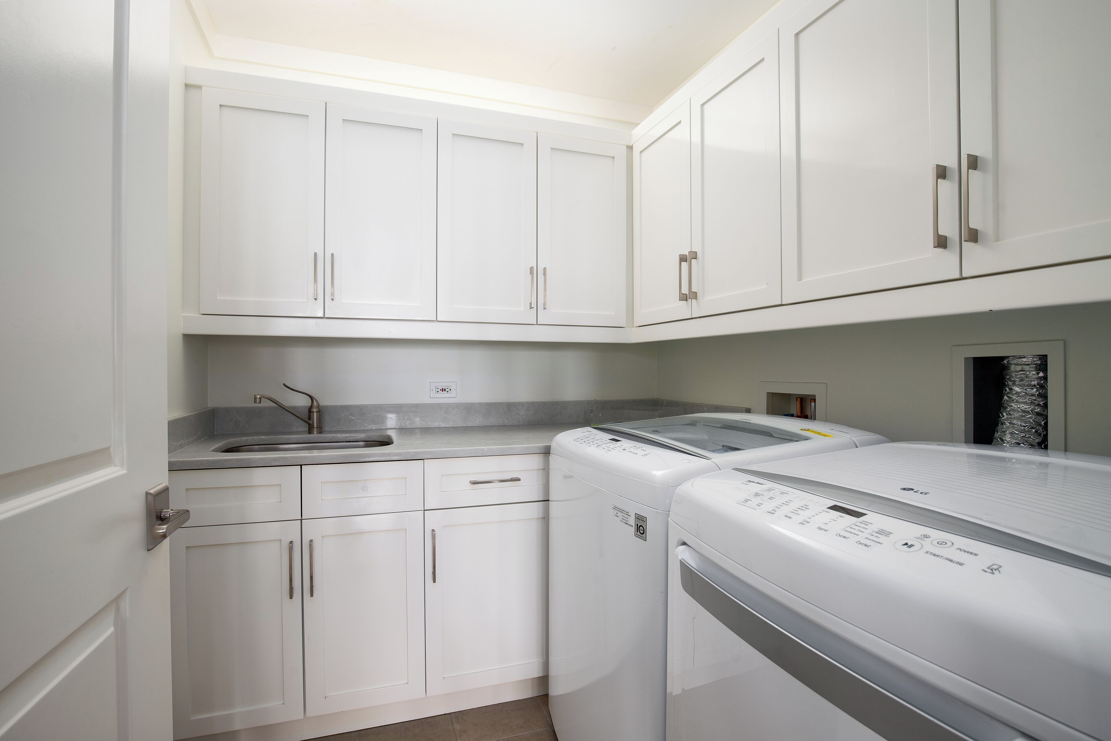 A laundry room with white cabinets, a washing machine, and a dryer.