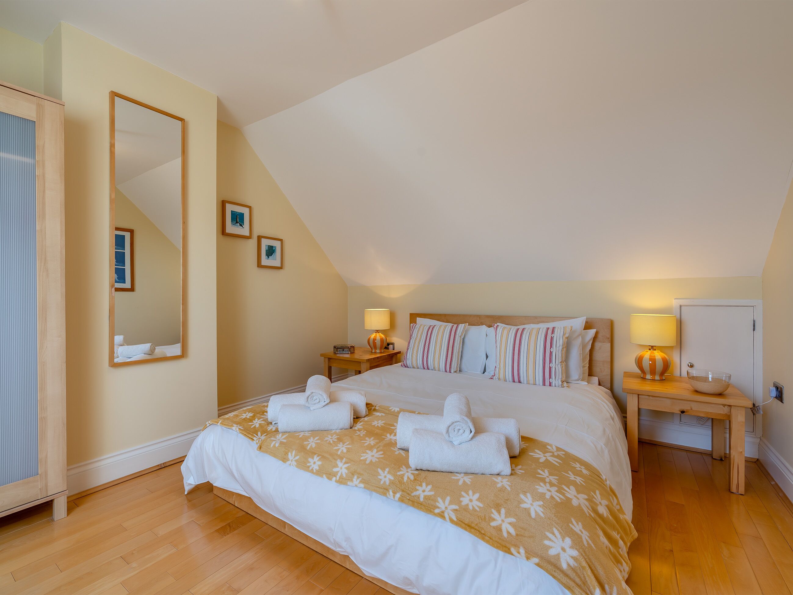 Ein Schlafzimmer mit einem großen Bett, zwei Nachttischen, einem Spiegel und einem Holzschrank.