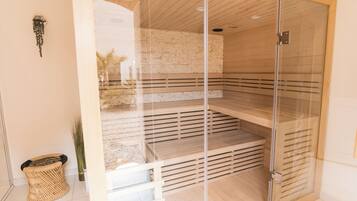 Sauna amb envà d'acer, seients de fusta i paret de rajola.