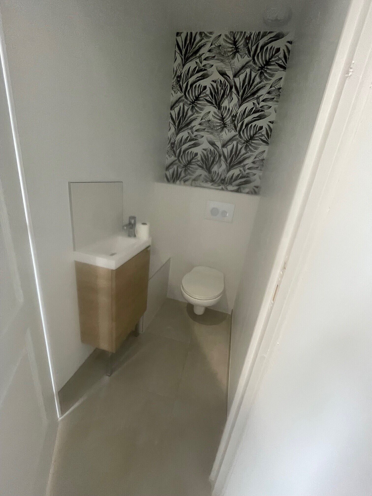 Een kleine badkamer met toilet, wastafel en spiegel.