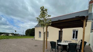 A building with a covered patio area, outdoor seating, and a gravel ground.