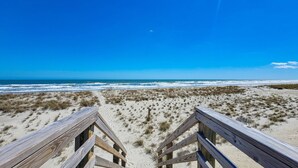 A beach with wooden boardwalks leading to the ocean, sandy dunes, and a clear blue sky. - Beachcomber – Small Space, Big Paradise! (Topsail Beach)