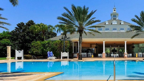 A large swimming pool with a covered area and palm trees. - Reunion Retreat 4-Bedroom Home w/ Playful Touches (Kissimmee)