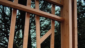 Una estructura de madera con piso de madera, posiblemente una terraza o porche, donde se ven dos toallas enrolladas.