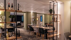 Un comedor moderno con mesas, sillas y botellas de vino.