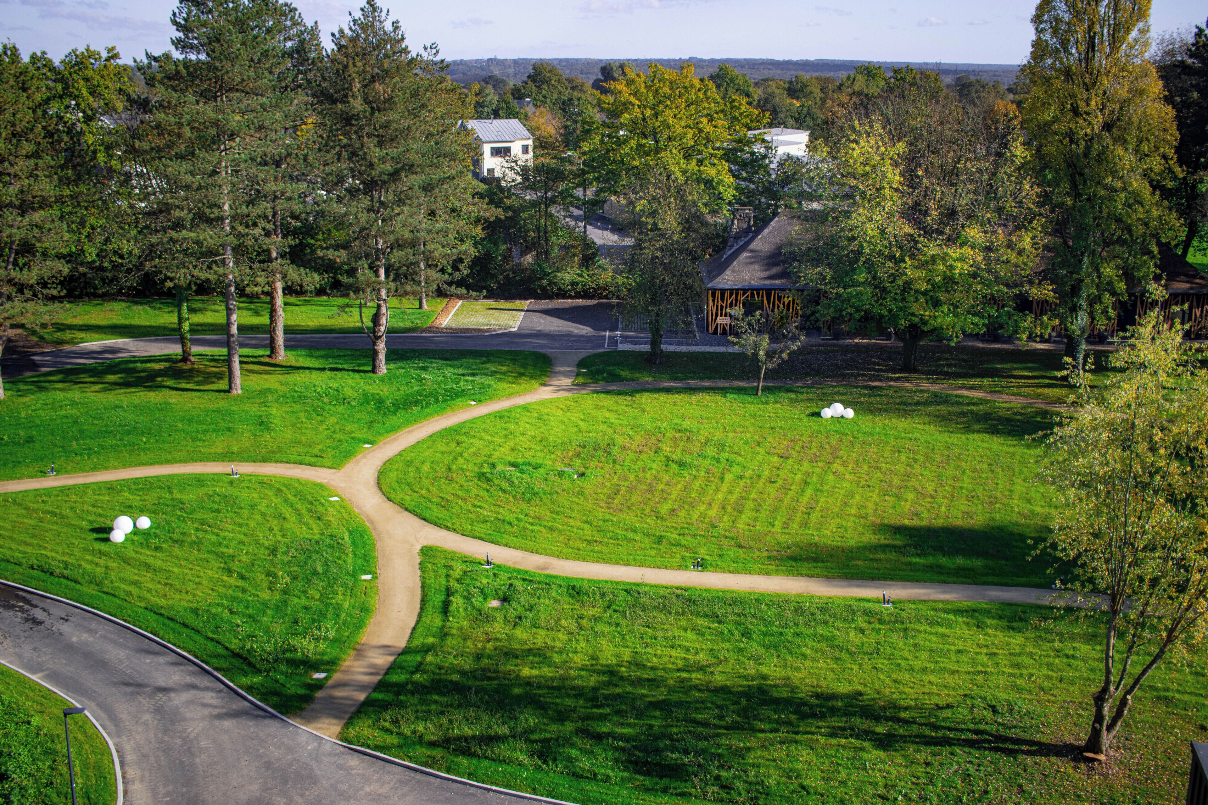 Ein Park mit einem gewundenen Pfad, Rasenflächen und Bäumen.