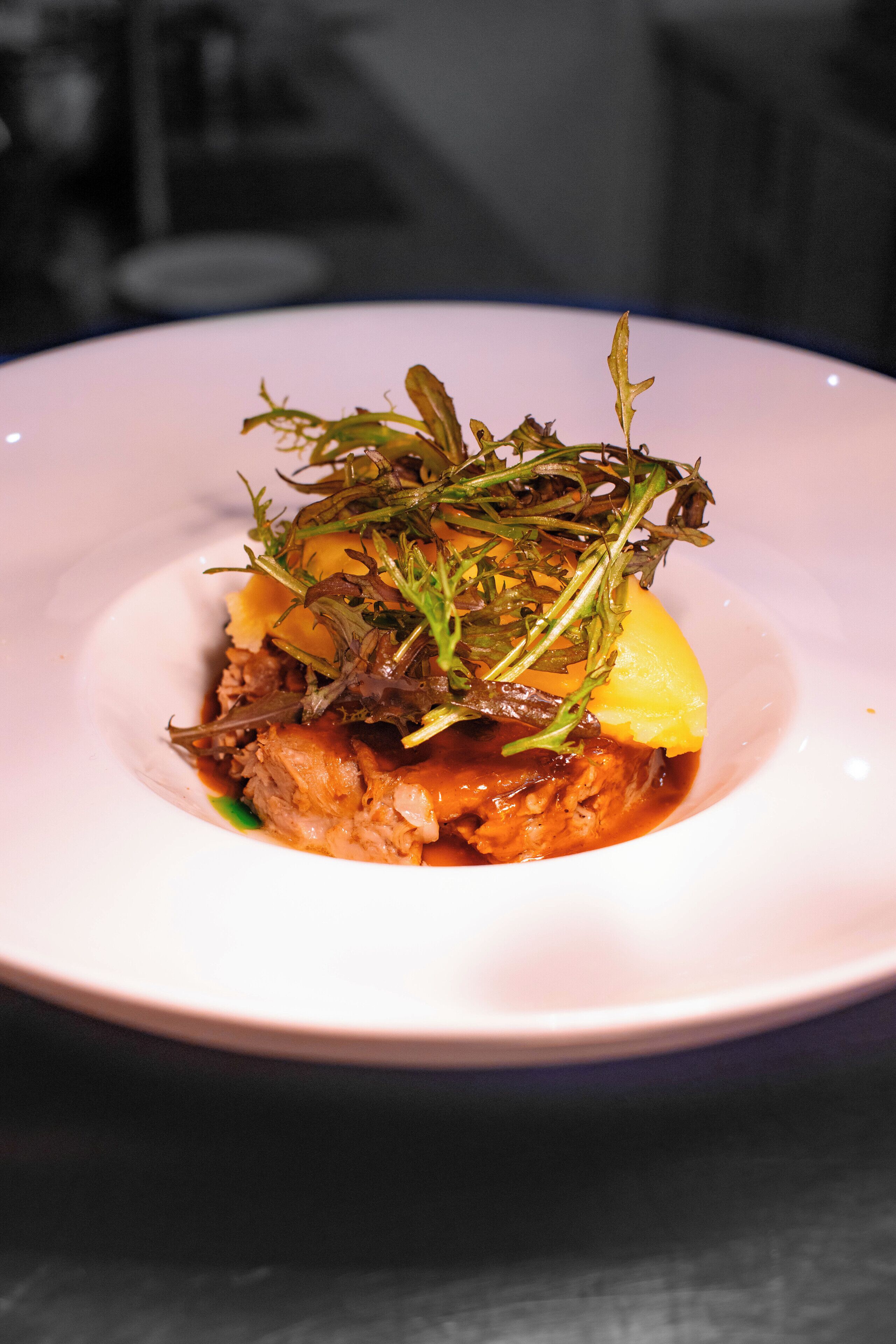 A plate of food with a garnish of greens and a slice of potato.
