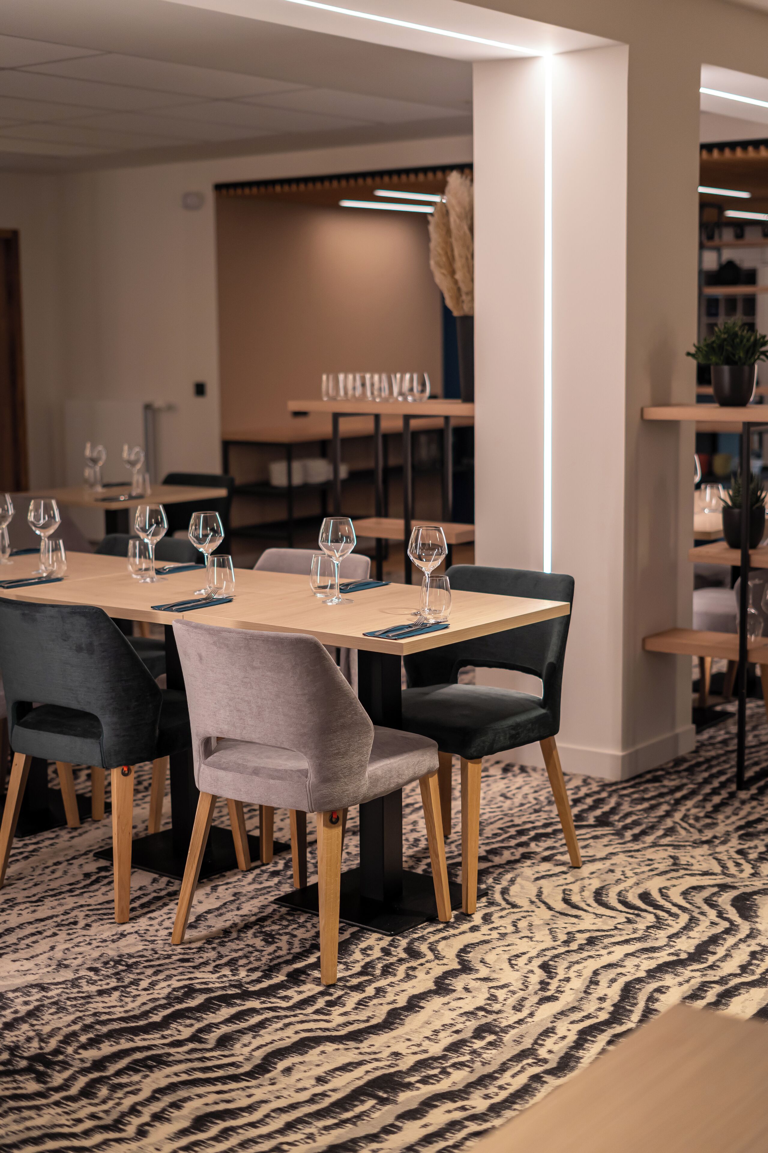A conference room with a long table, multiple chairs, and a patterned carpet.