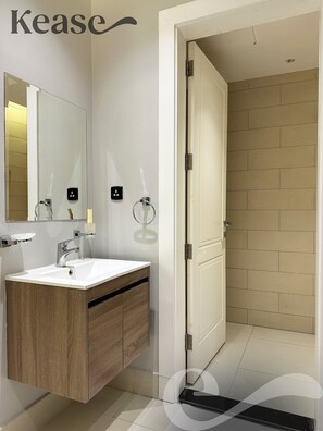 Ein modernes Badezimmer mit einem weißen Waschbecken, einer Holzanrichte und einem Spiegel.