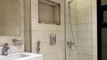 Et moderne badeværelse med vask i marmor, toilet og bruseniche.