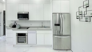Une cuisine moderne avec des meubles blancs, des appareils en acier inoxydable et un sol en marbre.