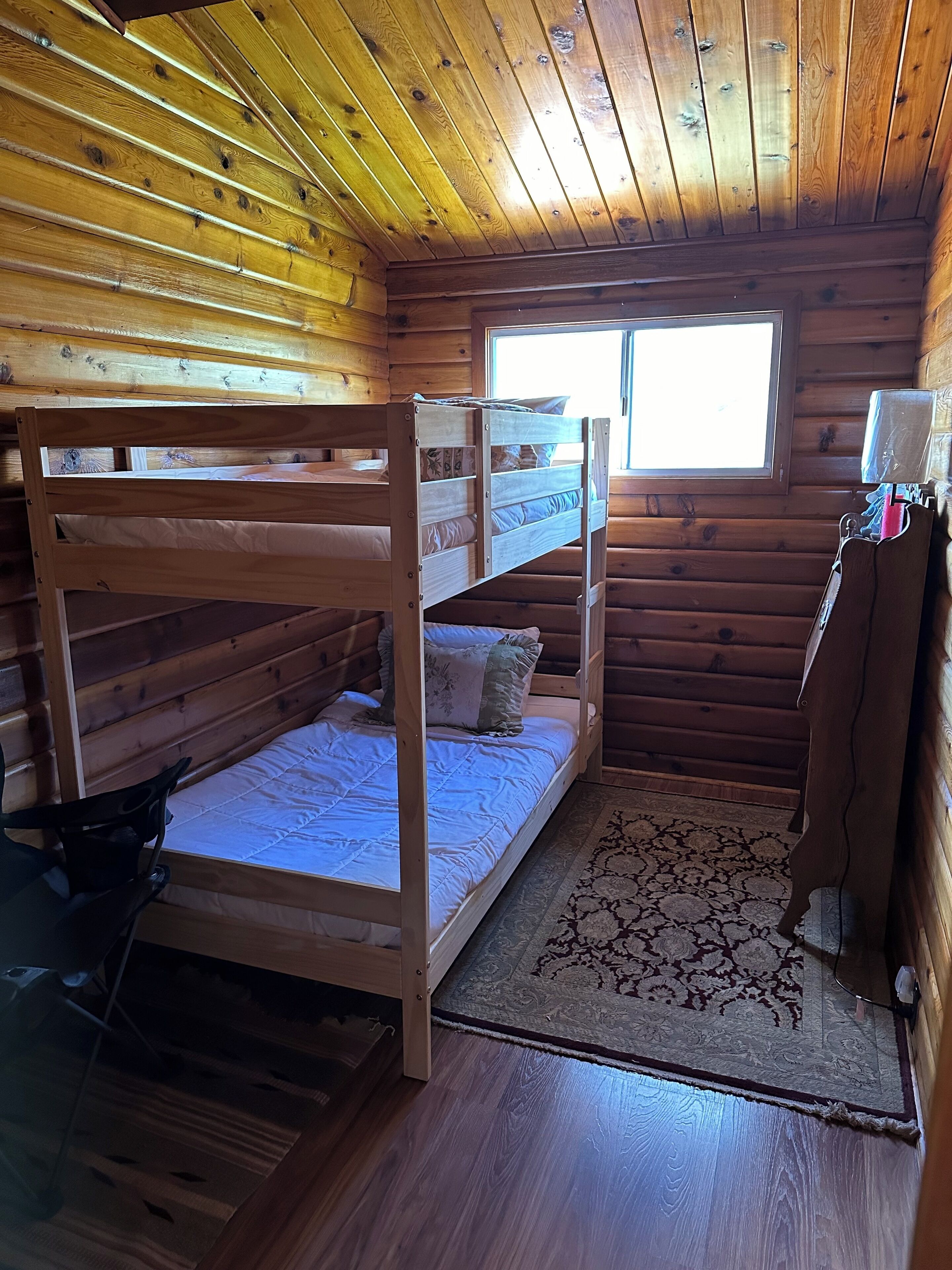 Une cabane aux murs en bois et dotée d’un lit superposé.