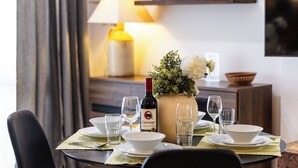 Une table à manger dressée avec des assiettes, des verres, une bouteille et un vase rempli de fleurs.