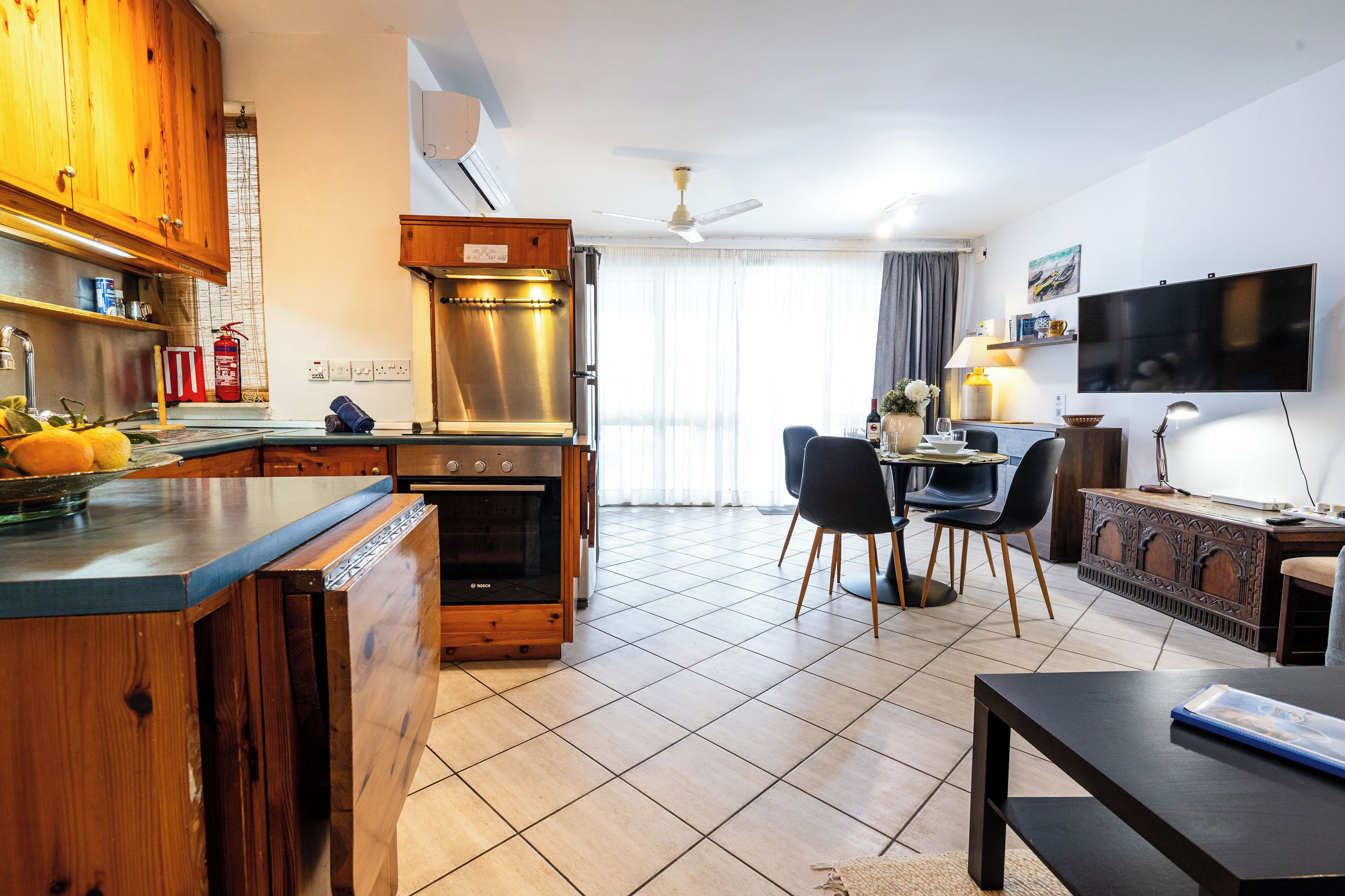 Une cuisine moderne avec des meubles en bois, un four encastré et un coin repas comprenant une table et des chaises.
