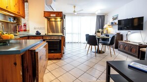 Une cuisine moderne avec des meubles en bois, un four encastré et un coin repas comprenant une table et des chaises.