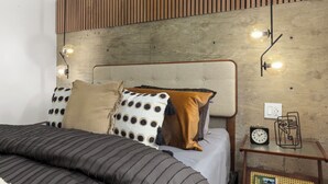 Ein modernes Schlafzimmer mit einem Holzkopfende, gestreifter Bettwäsche und einem Nachttisch mit einer Uhr und einem dekorativen Gegenstand.