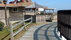 A wooden boardwalk leading to a building with a sloped roof and a small covered area with a sign. - Beach and Tennis Resort Villa (Hilton Head Island)