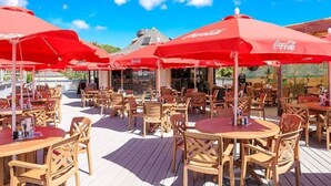 An outdoor dining area with red umbrellas and wooden tables and chairs. - Beach and Tennis Resort Villa (Hilton Head Island)
