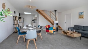 A modern living room with a dining area, a staircase, and a sofa. - Recent house in Pornic, 500m from the beach for 5 (Pornic)