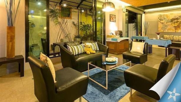 Una sala de estar moderna con un sofá, sillones, una mesa de centro y una zona de escritorio con una lámpara.