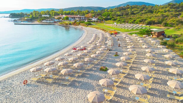A beach with rows of sun loungers and umbrellas, a lifebuoy, and a view of the sea and hills in the background. - Amasea Resort (San Teodoro)