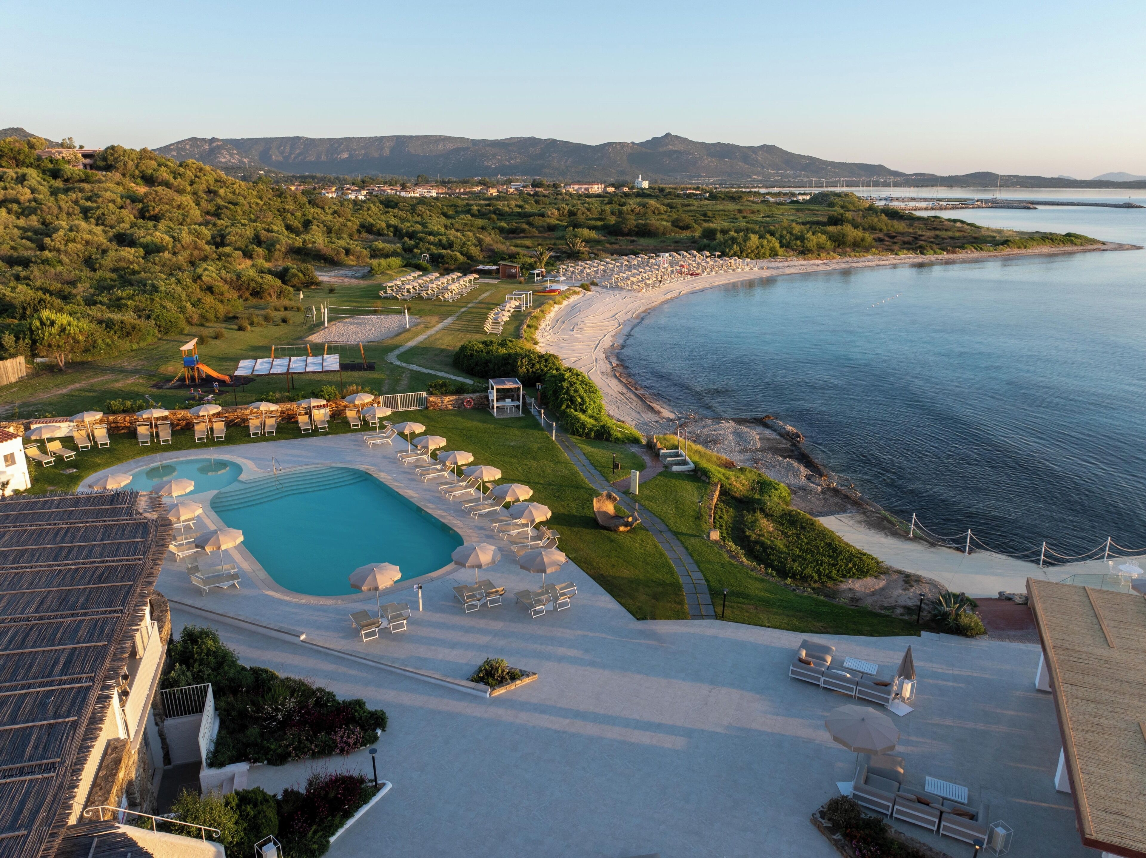 A resort with a swimming pool, lounge chairs, and a beach area.