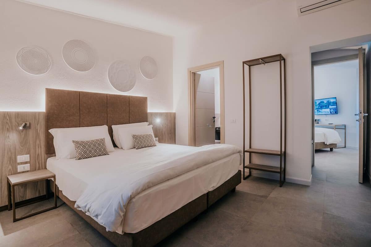 A modern bedroom with a large bed, bedside tables, a wardrobe, and a walk-in closet.