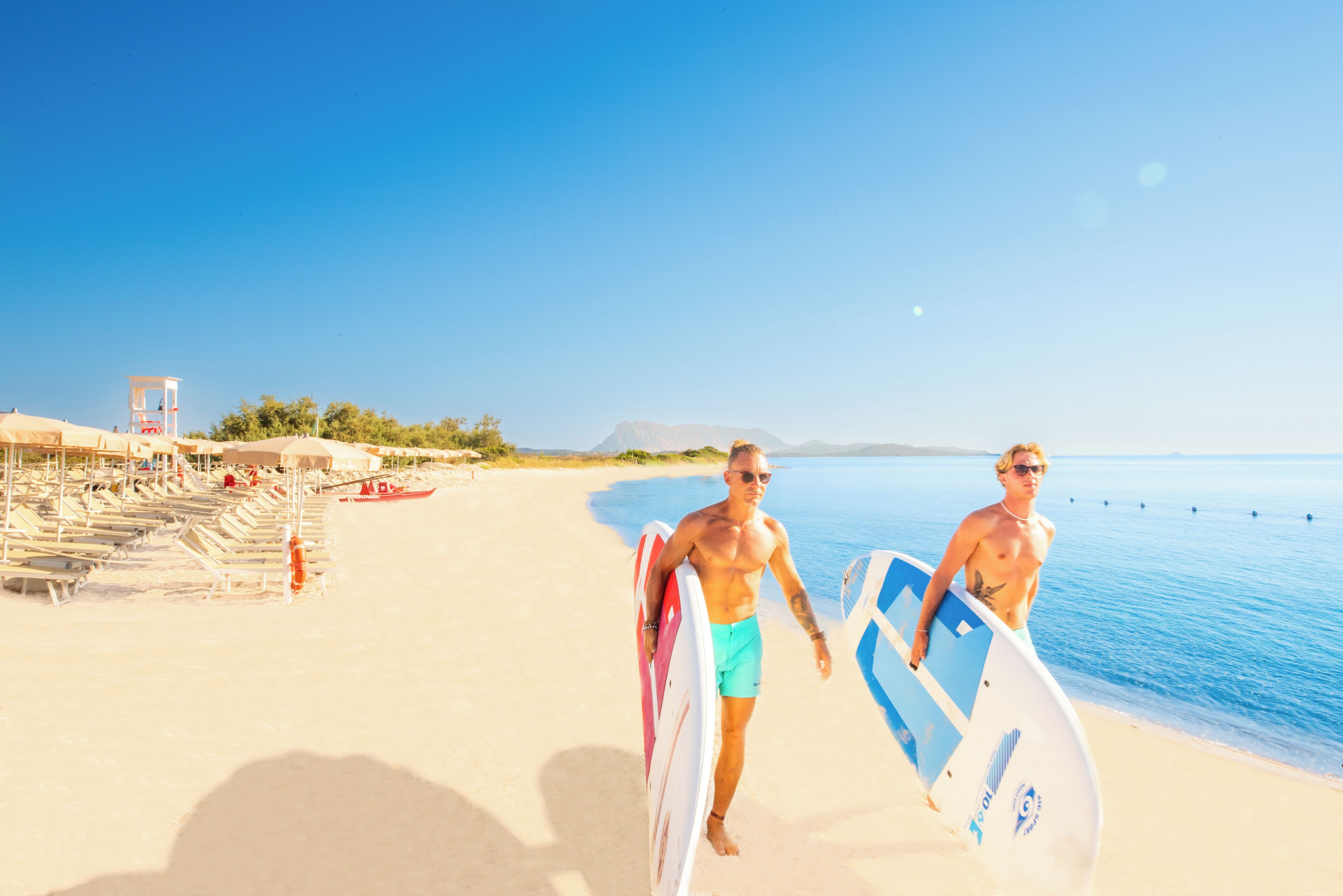 Ein Strand mit Liegestühlen, Sonnenschirmen, einem Rettungsboje und einem Rettungsturm.