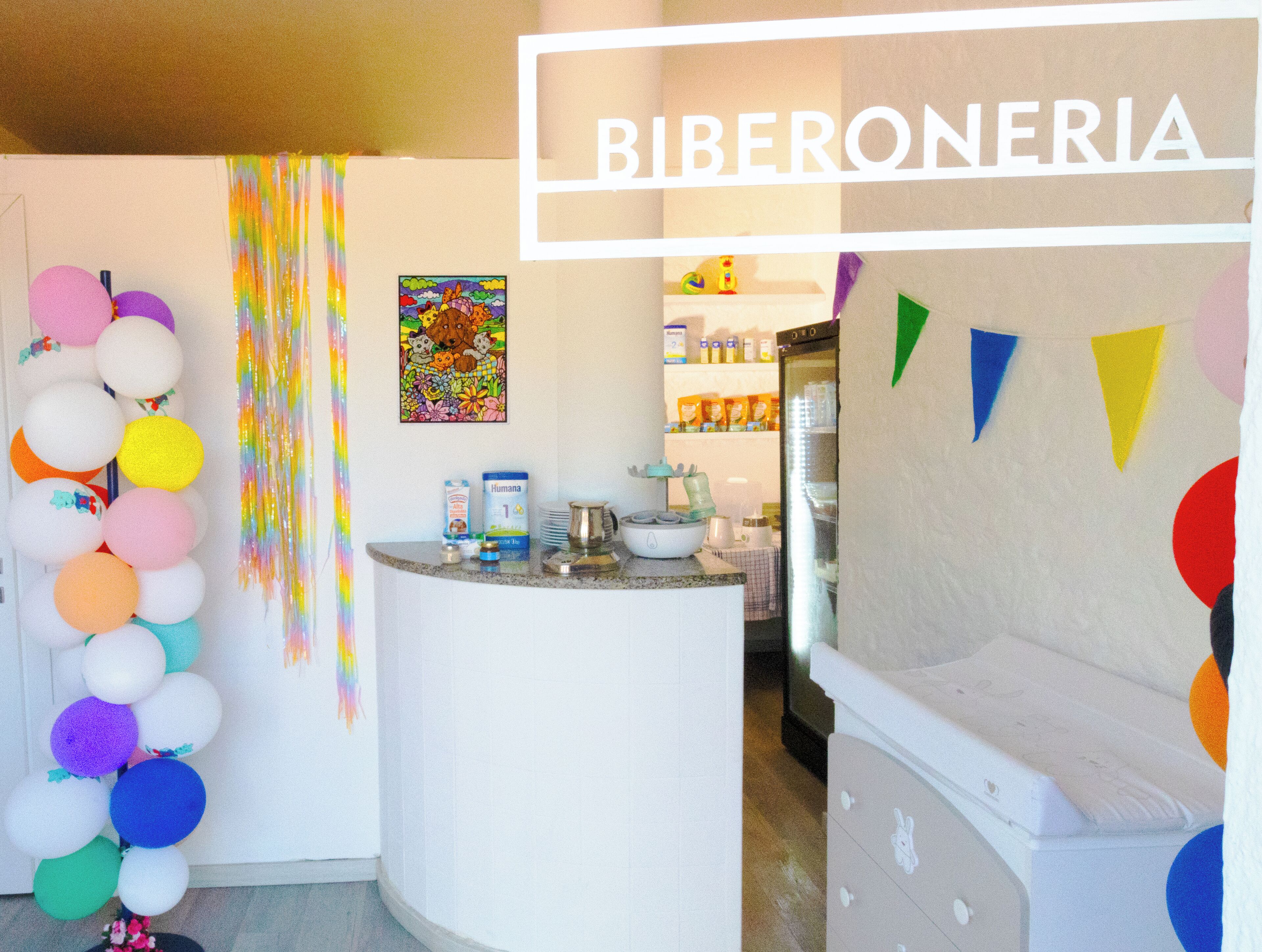 A kitchen area with a counter, balloons, and a refrigerator.