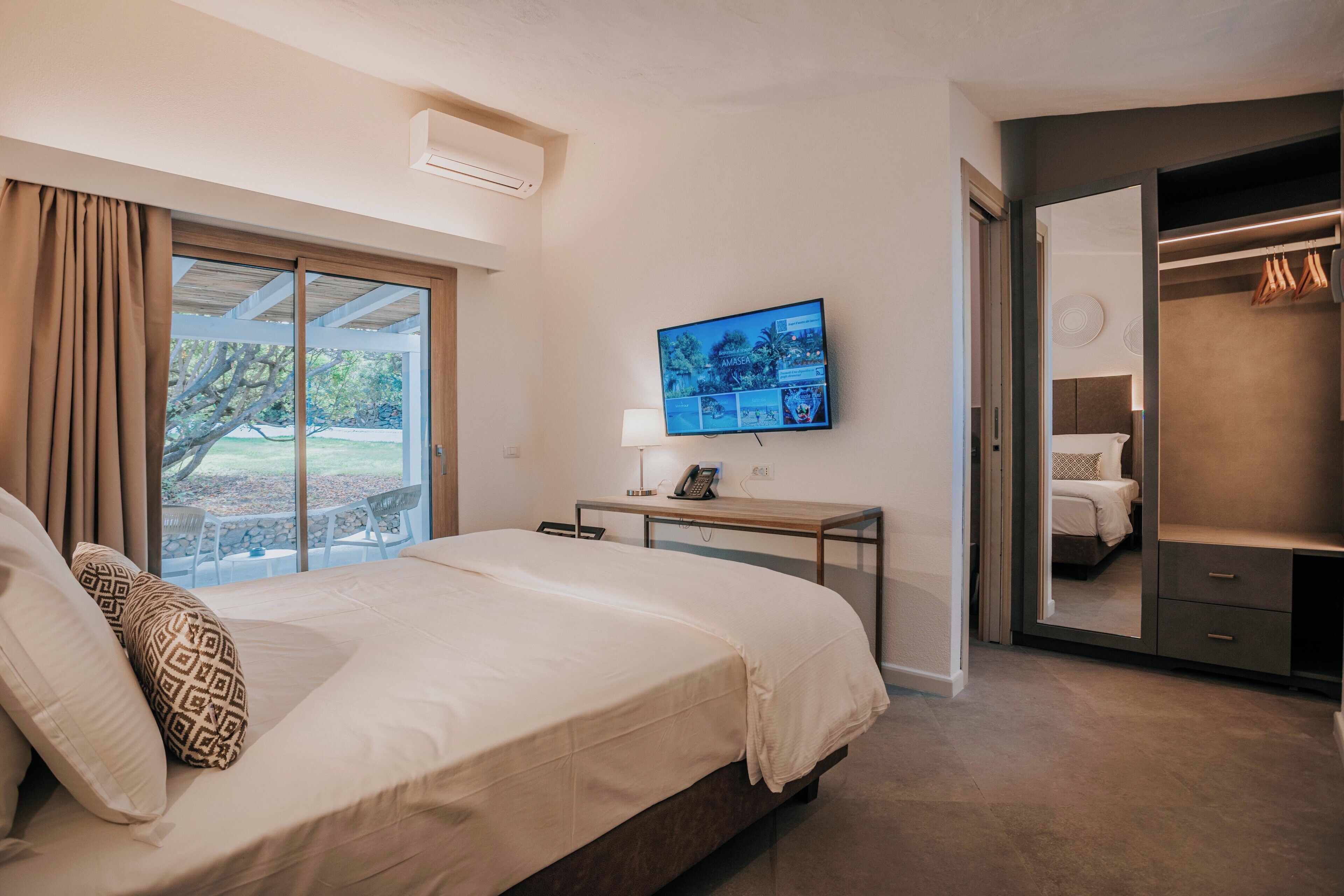 A bedroom with a bed, a TV, a desk, and a closet.