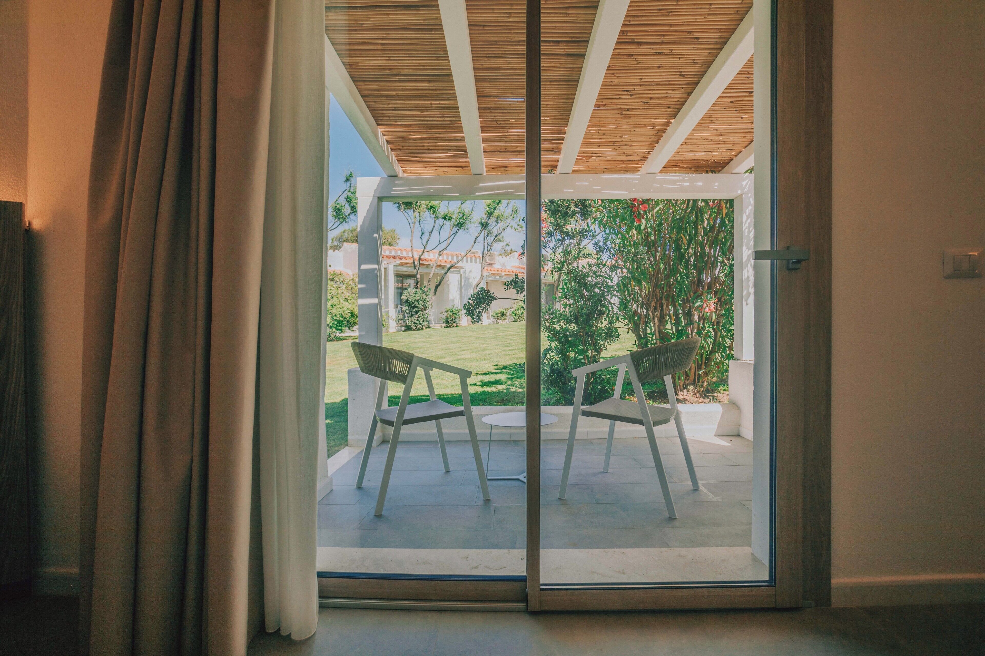Une porte-fenêtre coulissante donnant sur un patio extérieur équipé de deux chaises et d’une petite table.