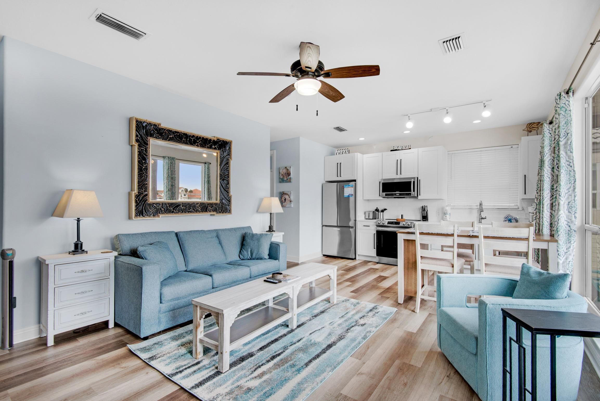 A modern living room with a blue sofa, a white coffee table, and a ceiling fan.