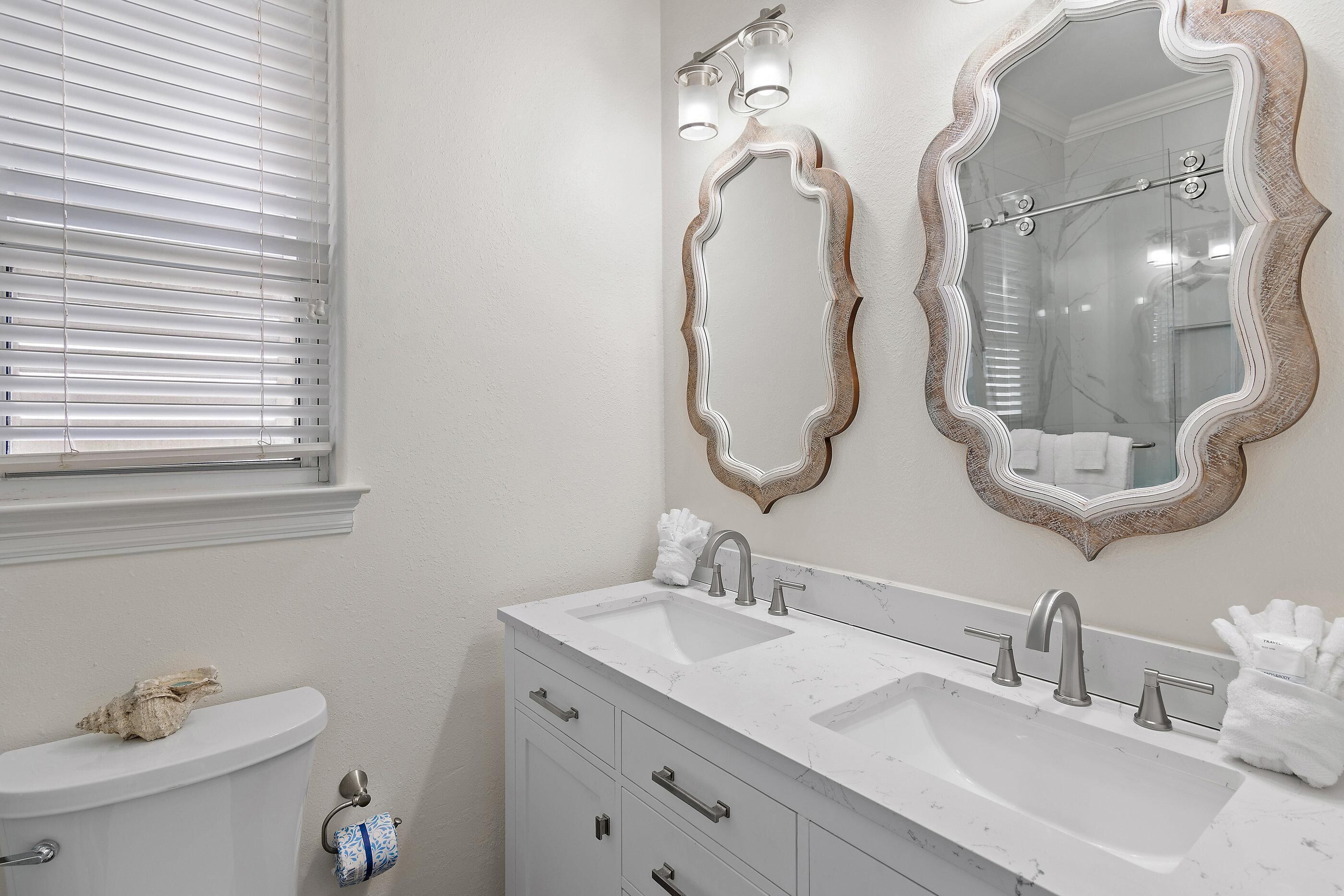 A bathroom with a toilet, two sinks, and two mirrors with ornate frames.