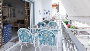 Ein Balkon mit einem weißen Metalltisch und Stühlen, einem Blumentopf und dekorativen Gegenständen an der Wand.