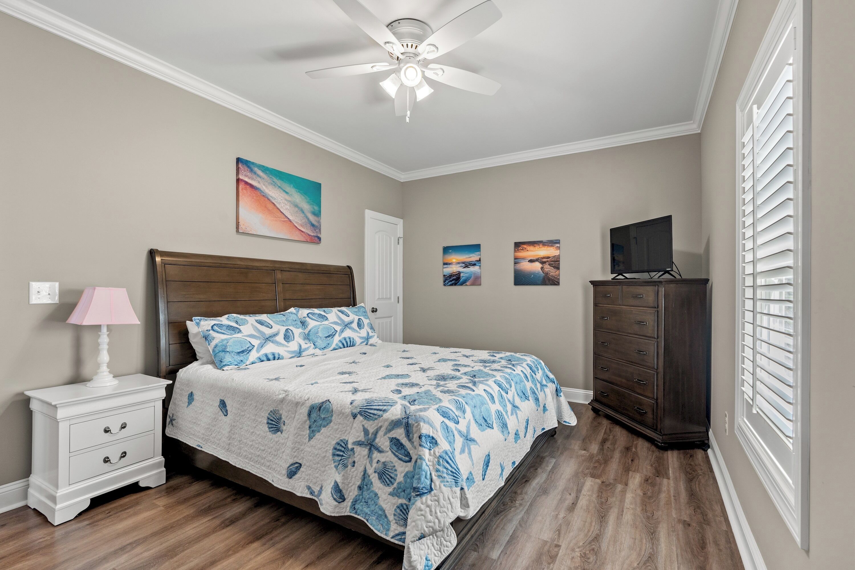A bedroom with a bed, a nightstand, a dresser, and a ceiling fan.