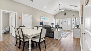A spacious living room with a dining area, a kitchen, and a ceiling fan.