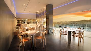 Un restaurante moderno con techo alto, ventanas amplias y vistas al paisaje.