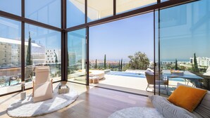 A spacious living area with a large glass window, a sofa, a chair, and a small table. - Leiro Residences - Preferred Hotels & Resorts (Fuengirola)
