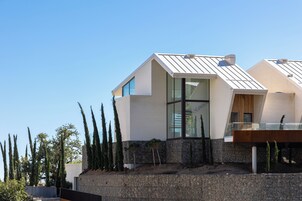 A modern house with a sloped roof, large windows, and a stone base.