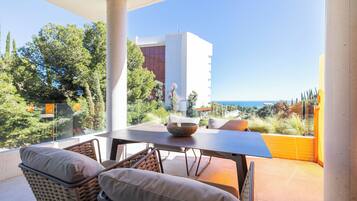 Un balcon avec une table et des chaises, une vue sur la mer et un bâtiment en arrière-plan.
