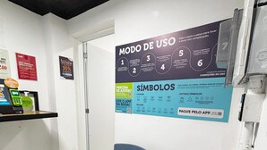 A room with a chair, a poster on the wall, and a shelf with items.
