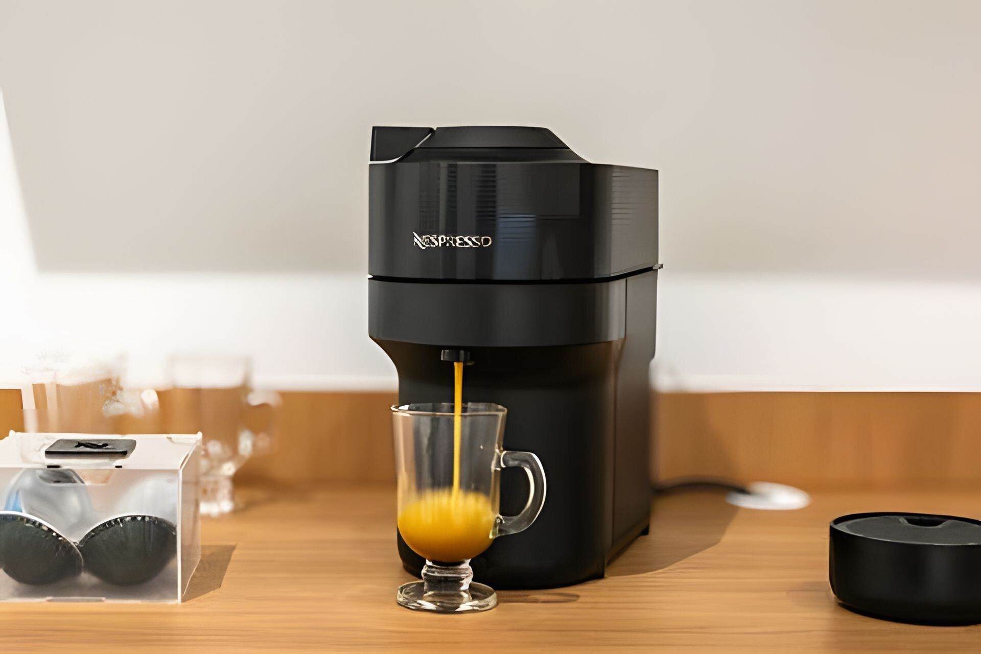 Een zwarte espressomachine schenkt koffie in een transparante glazen mok.