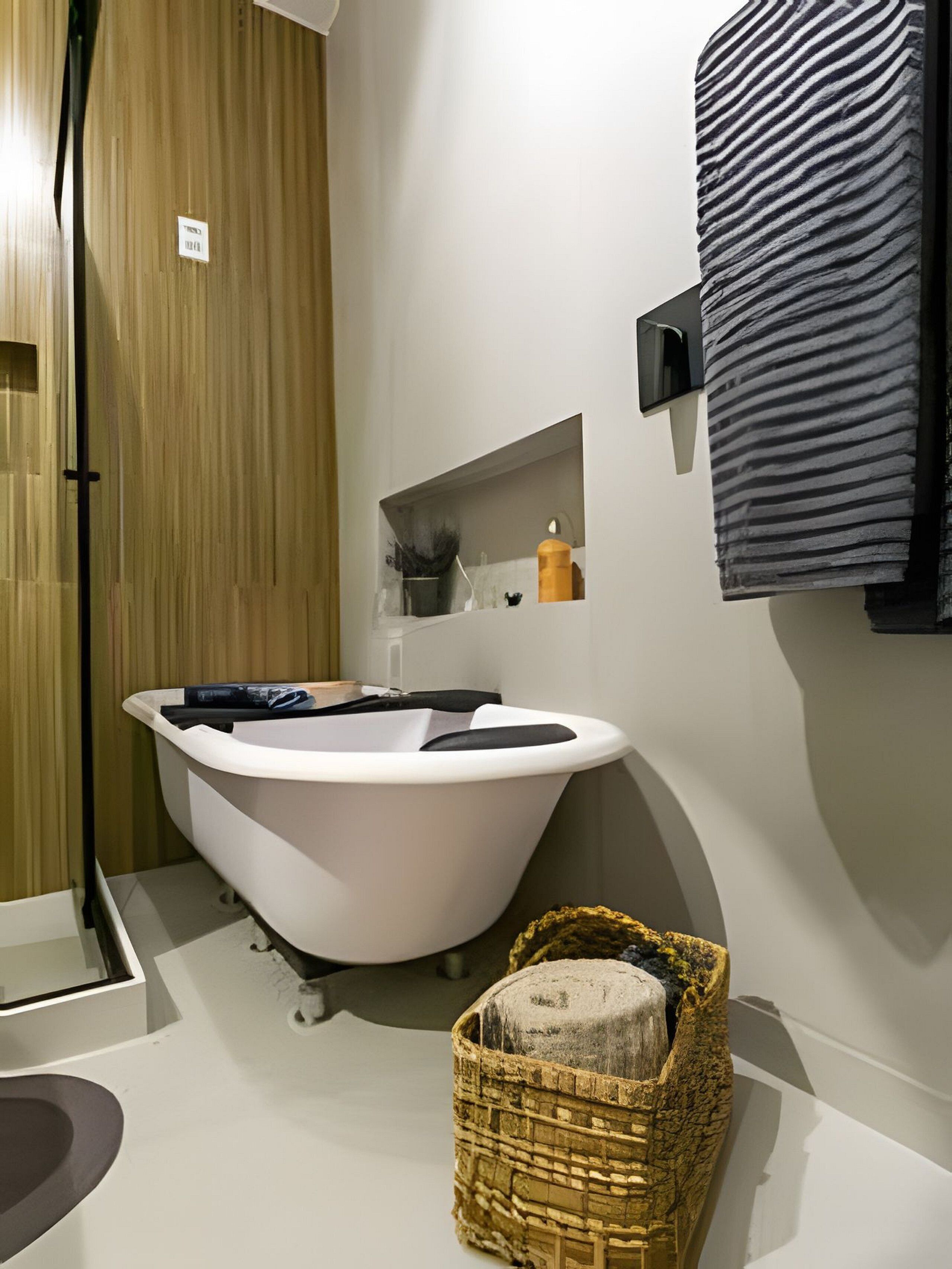 A modern bathroom with a freestanding bathtub, a wicker basket, and a towel rack.