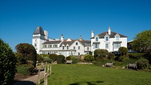 A large, white, multi-story building with a prominent tower, surrounded by well-maintained lawns and trees. - Riverside Retreat - One Bedroom Cottage, Sleeps 2 (Deganwy)