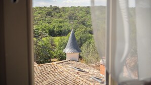 Vista desde una ventana sobre un paisaje verde y exuberante con una aguja de iglesia.