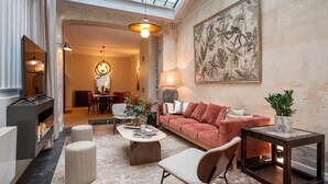 A spacious living room with a high ceiling, a large painting, a sofa, a coffee table, and a side table with a plant. - L'Atelier des Arts in Paris (Paris)