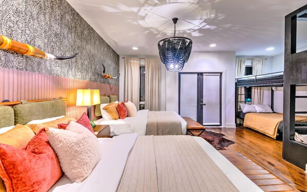 Une chambre d’hôtel avec deux lits, un grand lustre, un mur décoré de motifs et une vue sur l’extérieur.