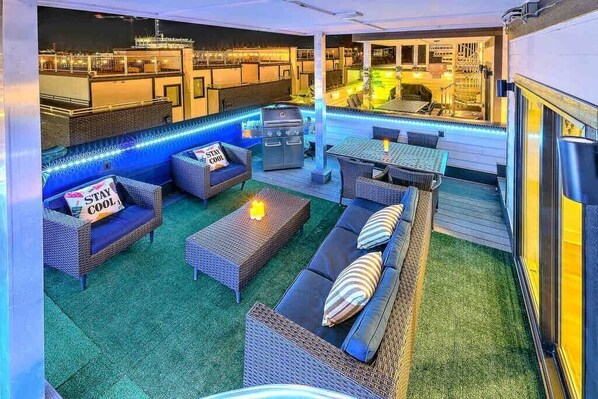 Ein Terrassenbereich im Freien mit Korbmöbeln, einem Grill und einer Poolbar.