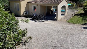 Ein kleines Gebäude mit einem Ziegeldach, einer überdachten Terrasse und einer Schotterauffahrt.