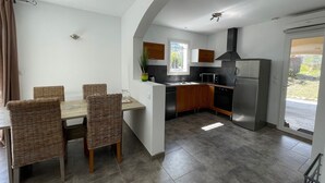 Eine moderne Küche mit Essbereich, ausgestattet mit einer großen Kochinsel, integrierten Geräten und Blick ins Freie.